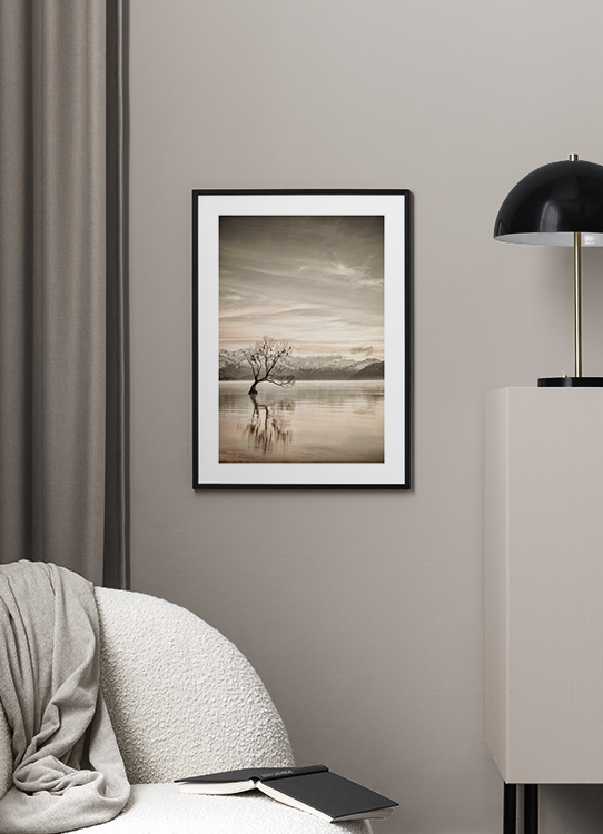  – Fotografia di un lago immobile con un albero in mezzo e montagne sullo sfondo