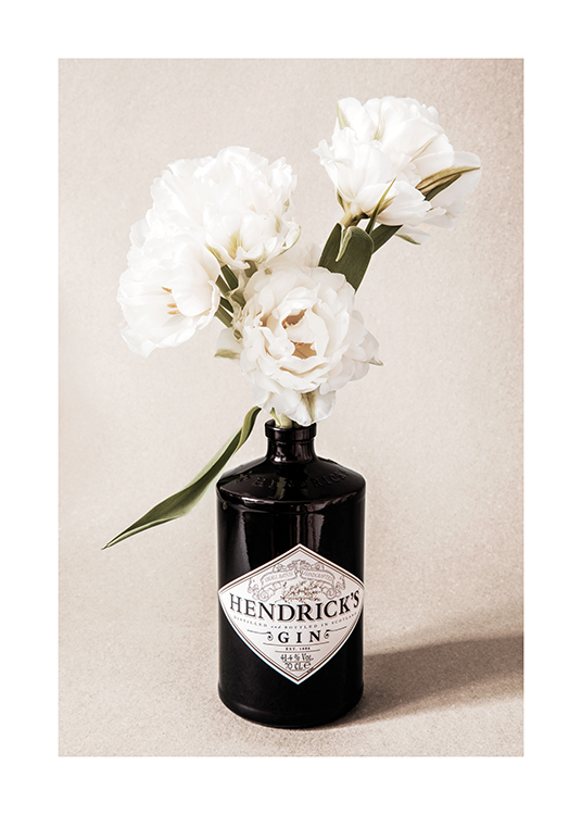  – Fotografie von weißen Blumen in einer schwarzen Ginflasche vor einem beigen, körnigen Hintergrund