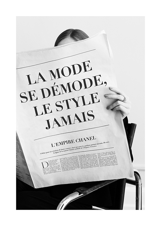 – Photographie en noir et blanc d’une femme tenant devant elle un journal avec des articles sur la mode